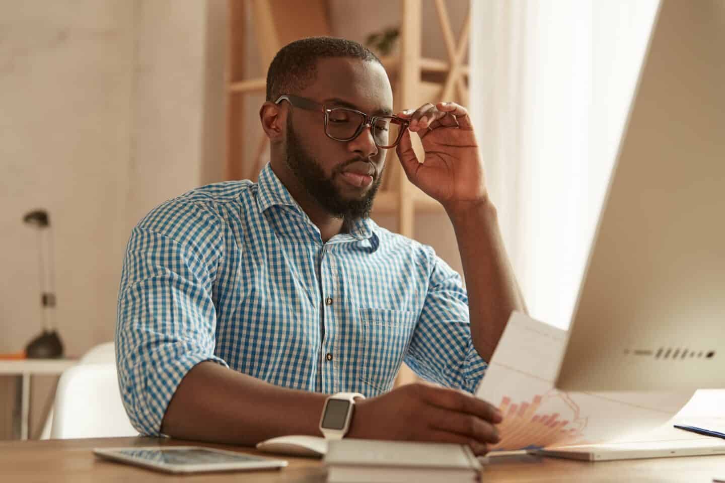 Full concentration. Smart young afro american man in glasses working on the computer while sitting